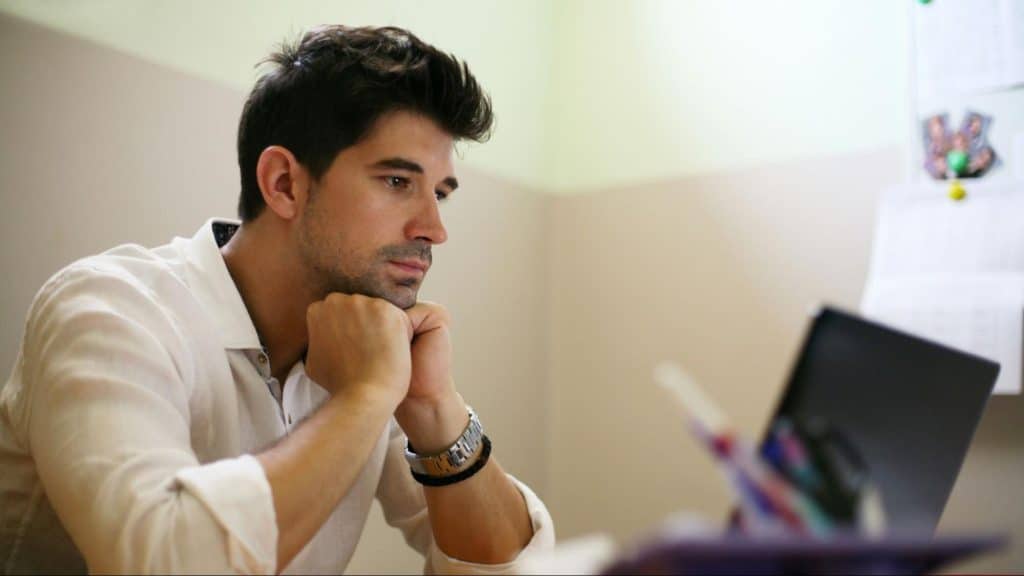A man looking hopeless while looking at the laptop