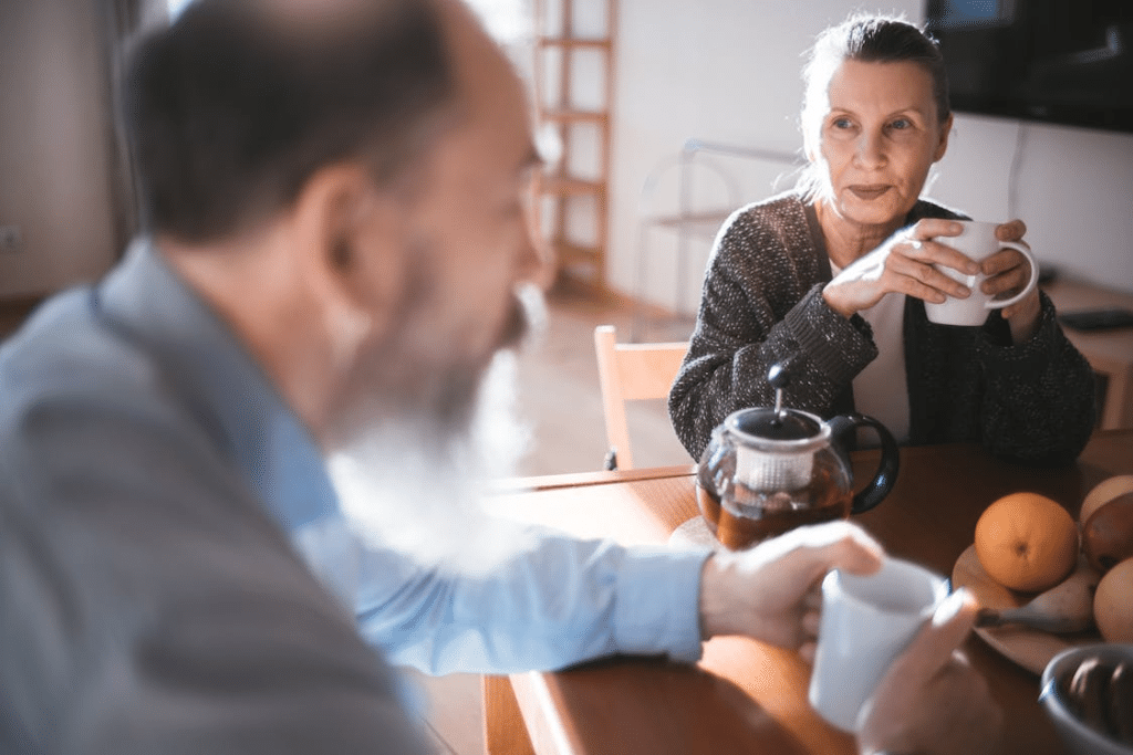 Mature couple sitting and having coffee, woman looking judgingly