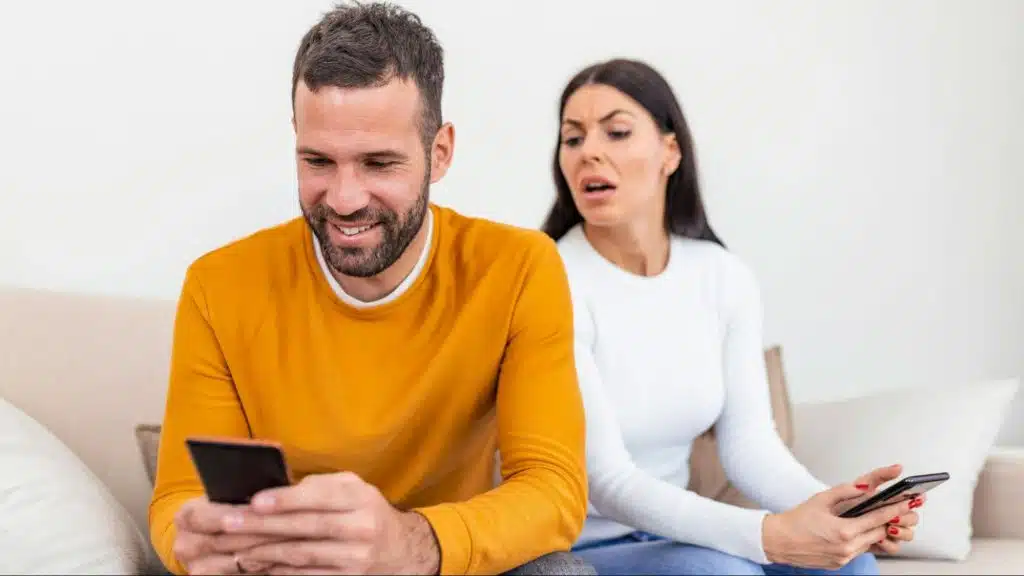 A man using a phone and a woman behind him