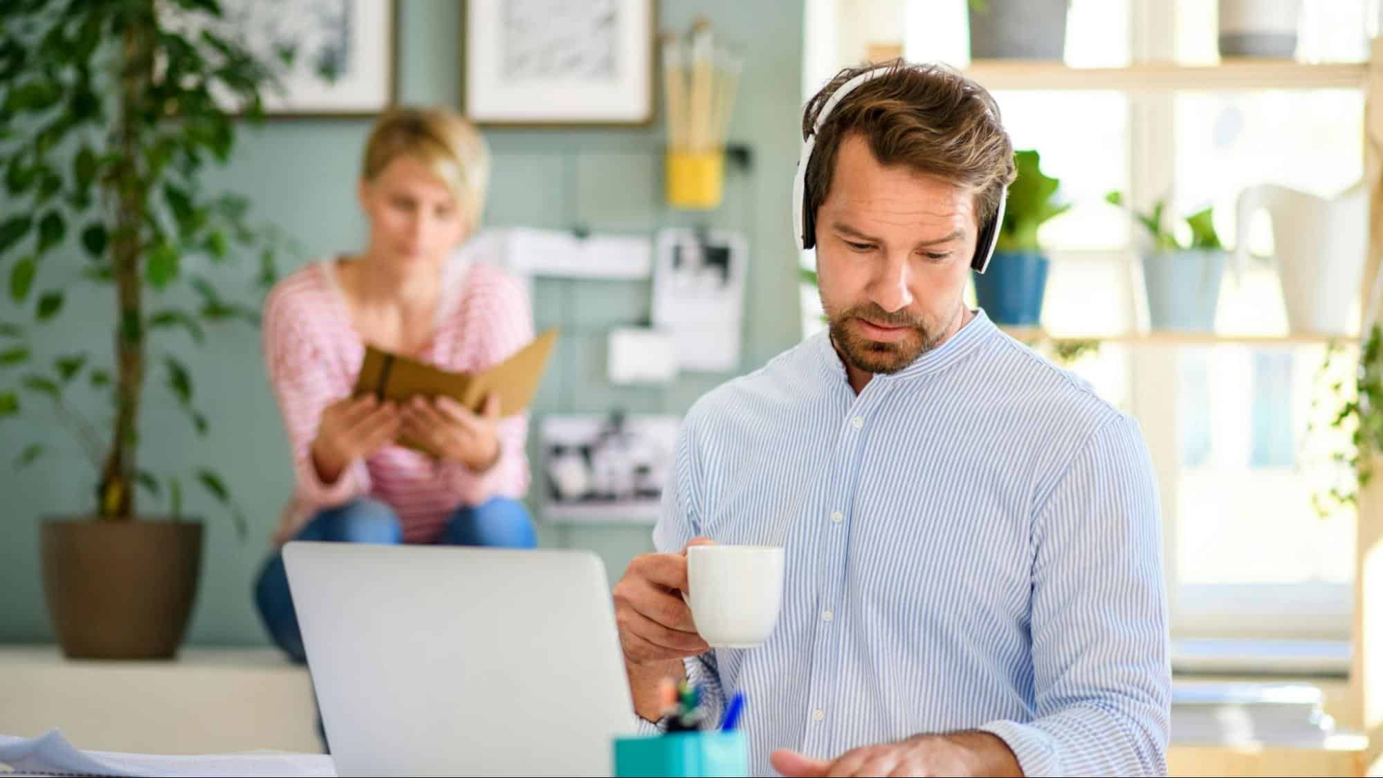 A man busy working and a woman reading behind him