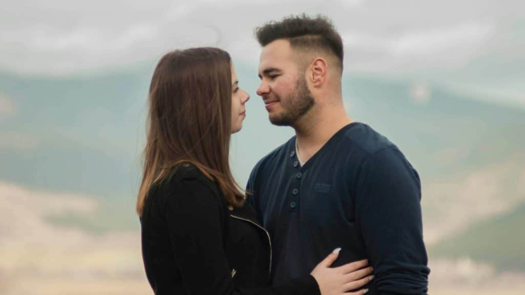 A man in a long-sleeved black shirt looking at a woman in a long-sleeved black shirt.