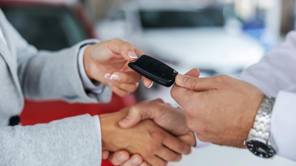 A person handing over car keys in a dealership.
