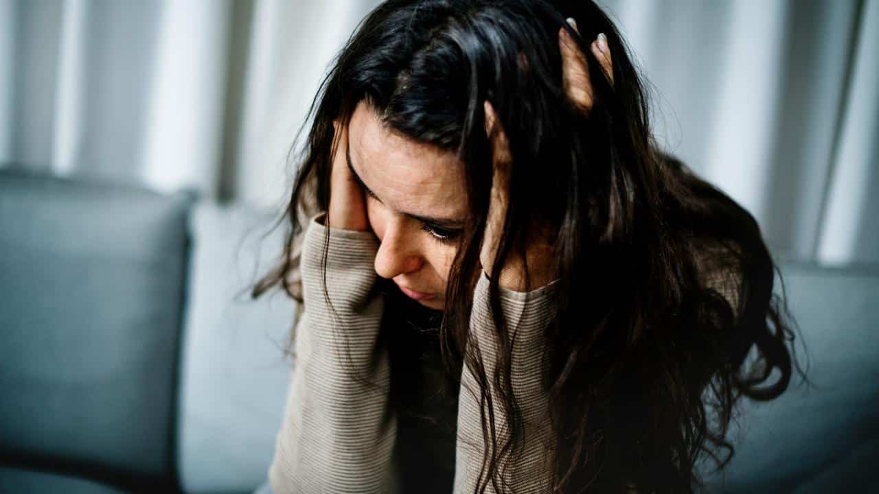 A distressed woman sitting with her head in her hands.