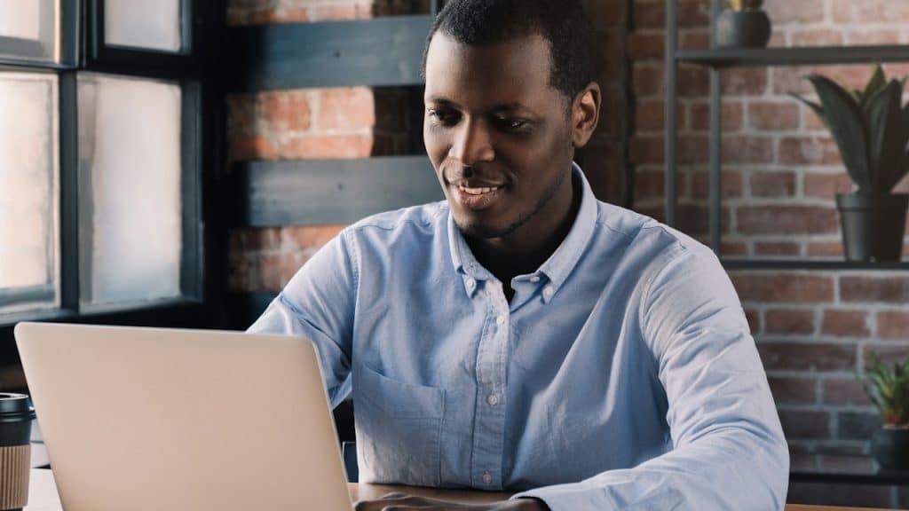 A man smiling and using a laptop. 