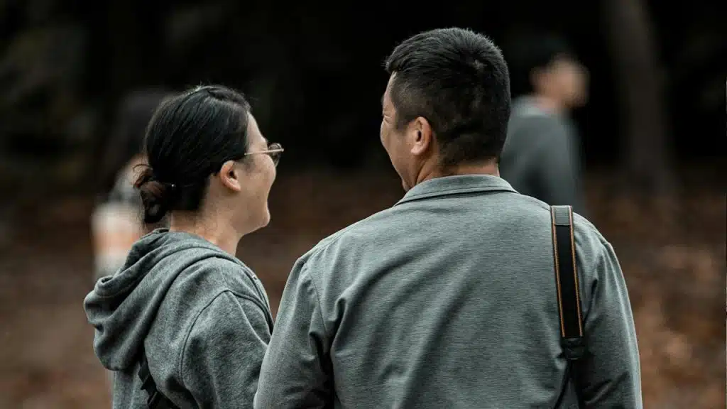 A couple standing with their backs to the camera and smiling at each other.