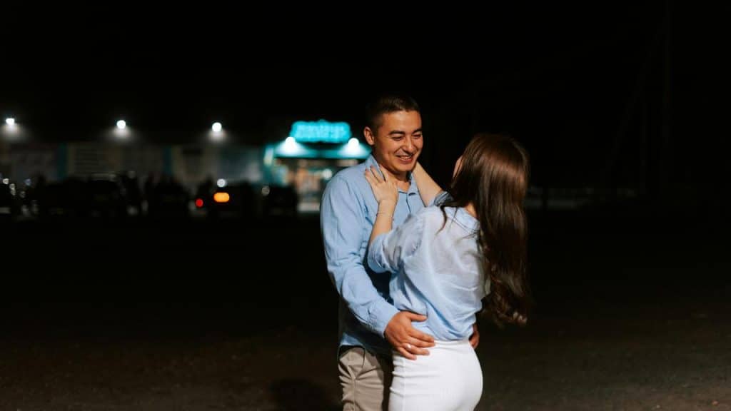 A couple embracing and smiling together outdoors at night.