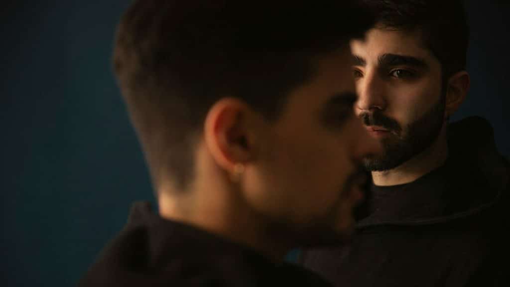 A man with a beard looks intently past the blurred profile of another man.