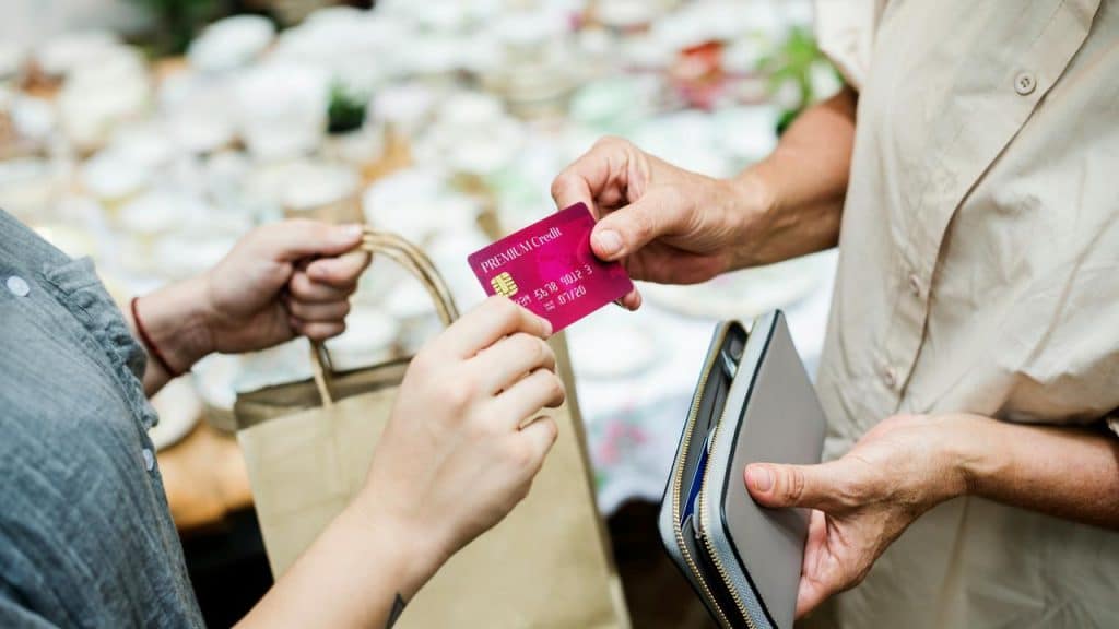 A person handing a credit card to a cashier during a purchase.