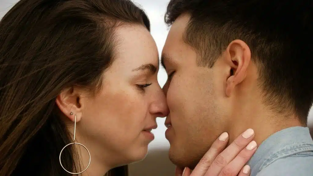 A close-up of a man and woman touching noses with their eyes closed.