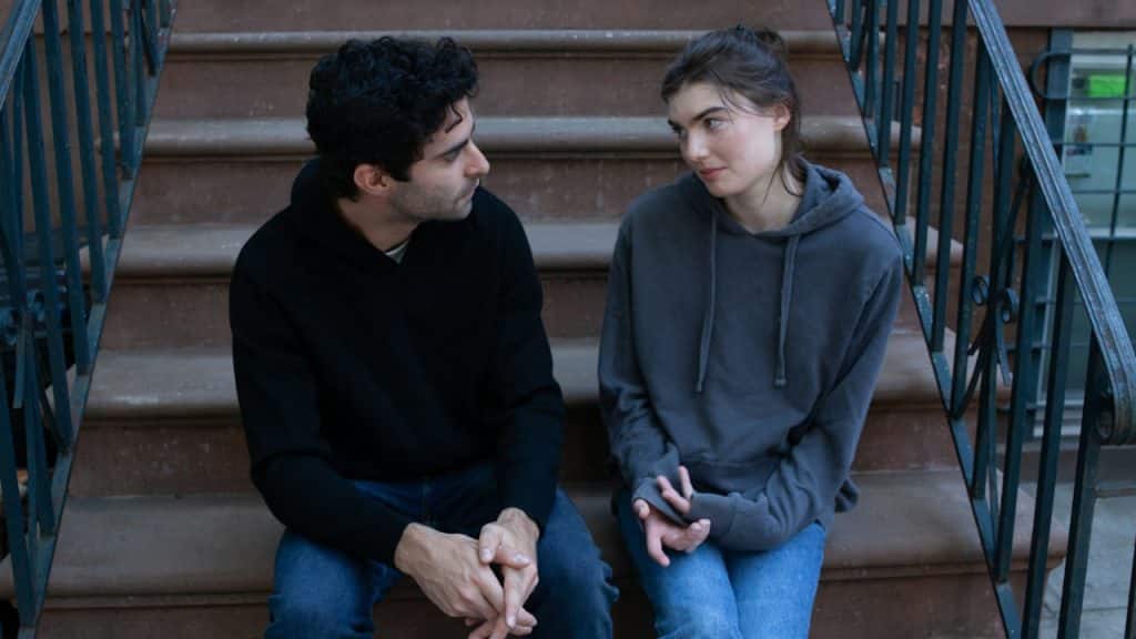 A man and a woman are sitting on the stairs and talking to each other.