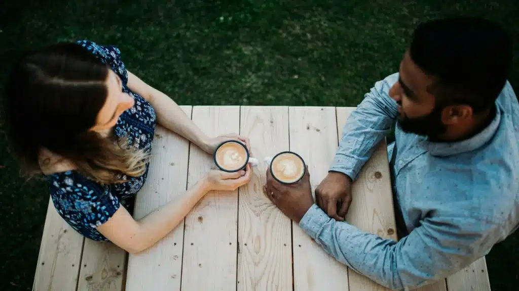 An overhead view of a man and woman holding mugs at a table.