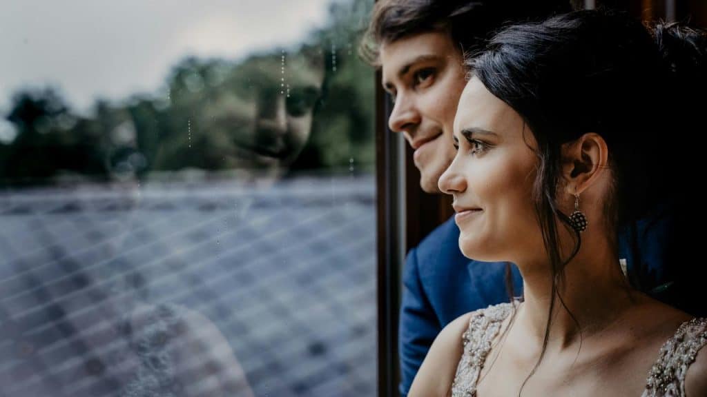 A couple gazing out a window with their reflections in the glass.