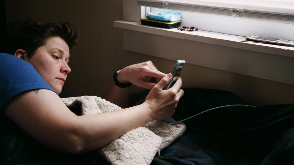 A person lying in bed looking at a smartphone.
