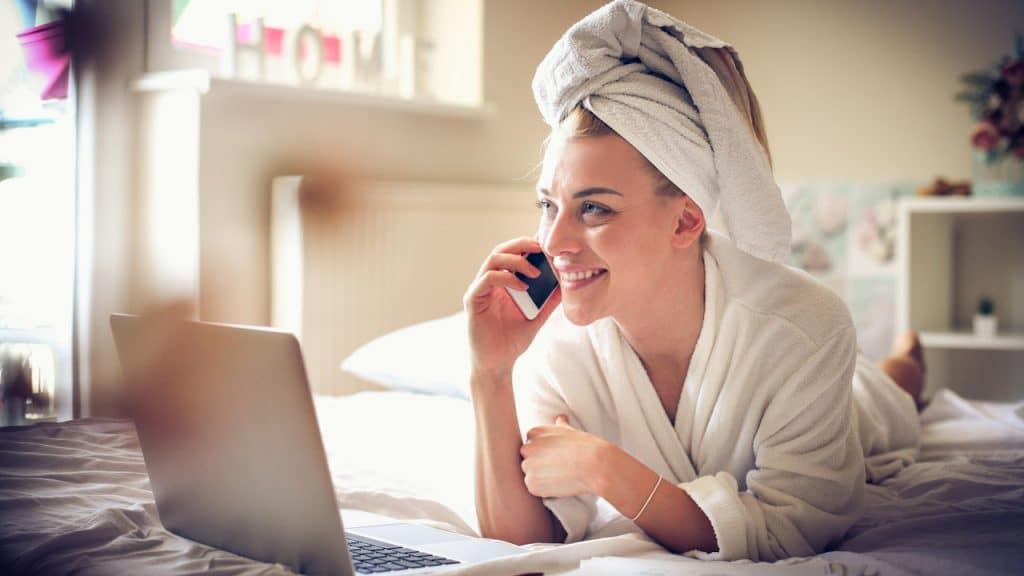 A business woman talking on phone after taking bath while sitting in front of a laptop.