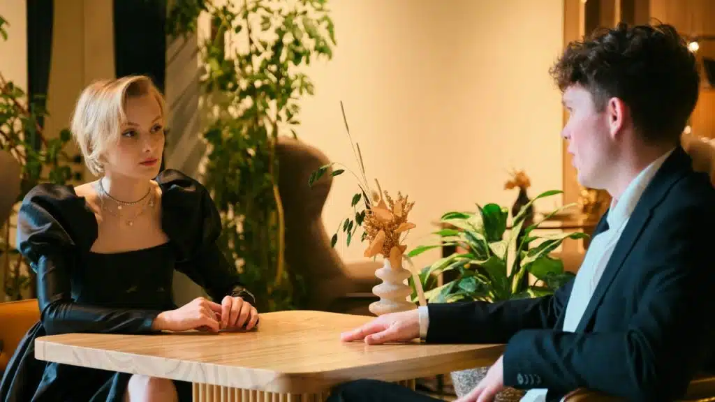 A woman in a black dress and a man in a suit sit at a table.