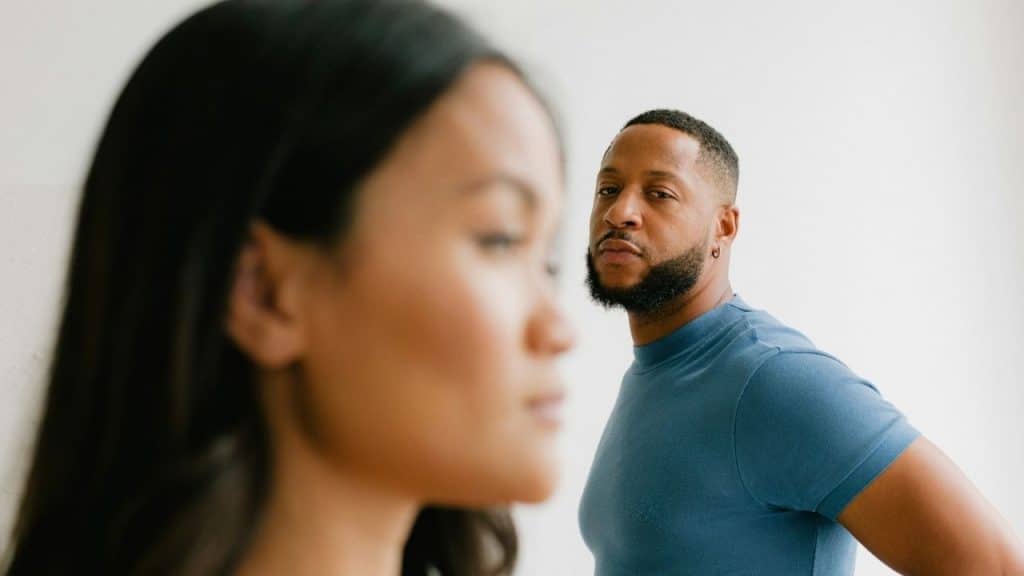 A man in a blue shirt looks toward a woman’s face, which is out of focus.