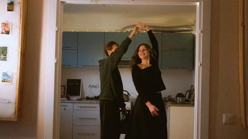 A couple dancing together in a cozy kitchen doorway at home.