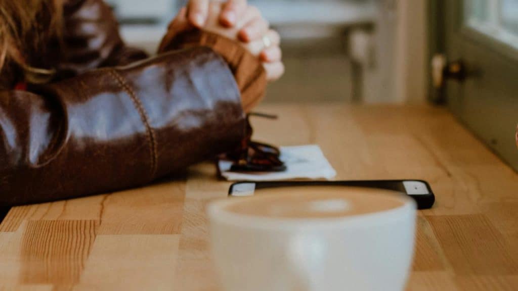 A coffee cup on a table with a phone and glasses nearby.