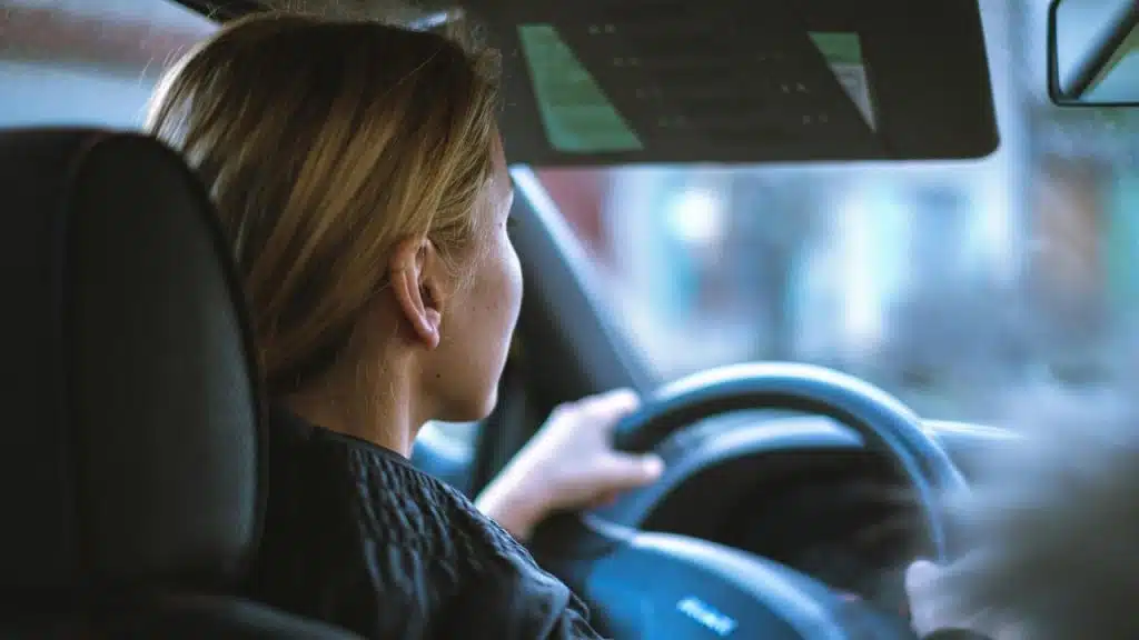 A person driving a car while looking ahead through the windshield.