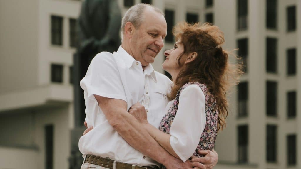 A man and a woman embracing each other in front of a building.
