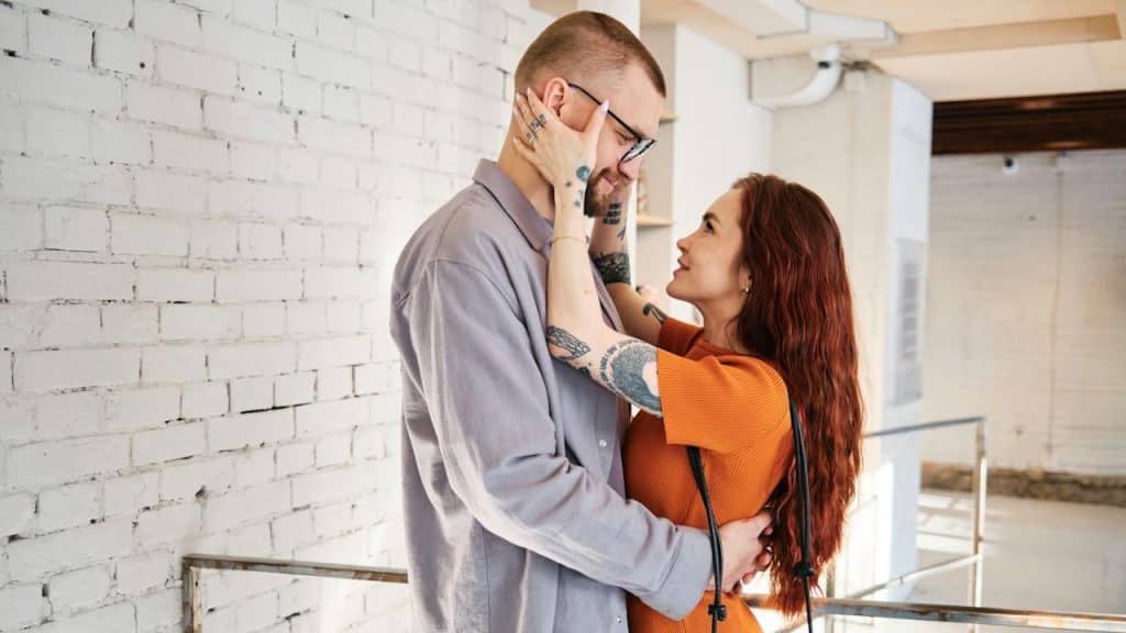 A woman holding her partner’s head and gazing lovingly into his eyes.