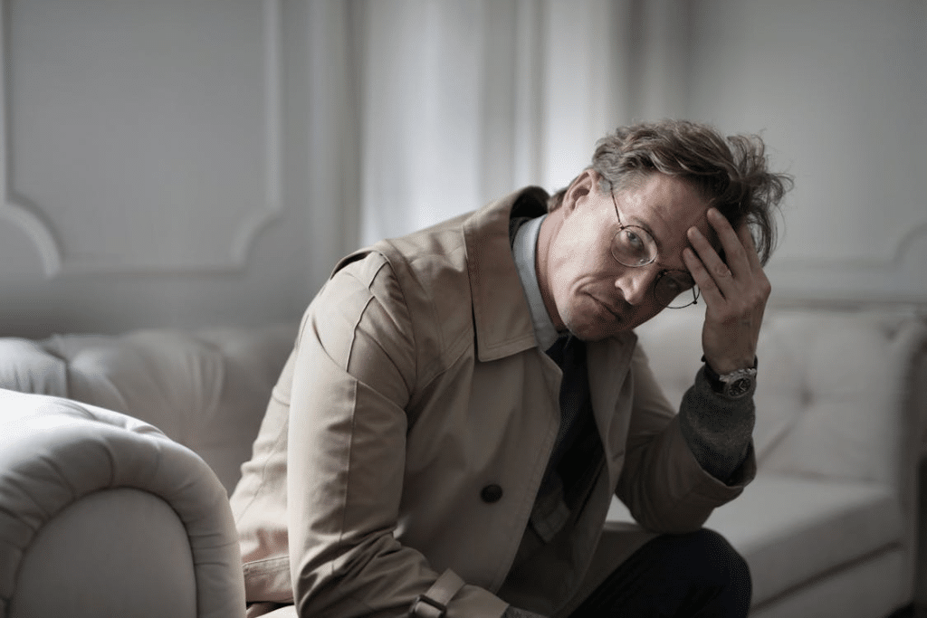 Thoughtful man in stylish outfit sitting on couch