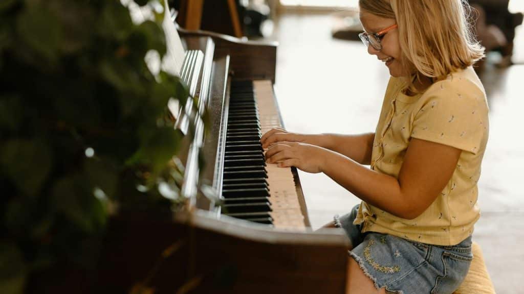 A young girl smiling while playing the piano.
