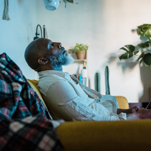A man sitting on a sofa while drinking a beer