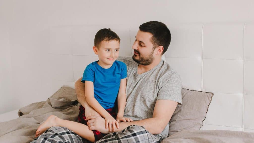 A father holding his son on a bed.