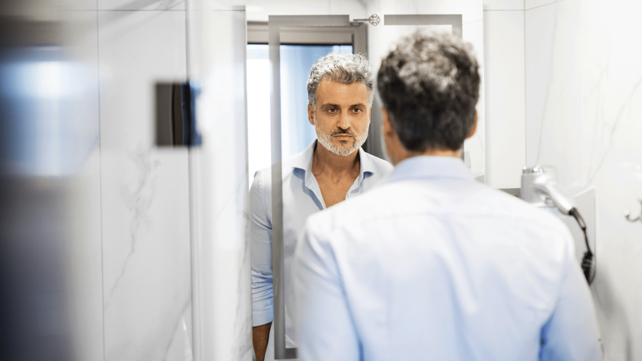 A man looking sadly at a mirror
