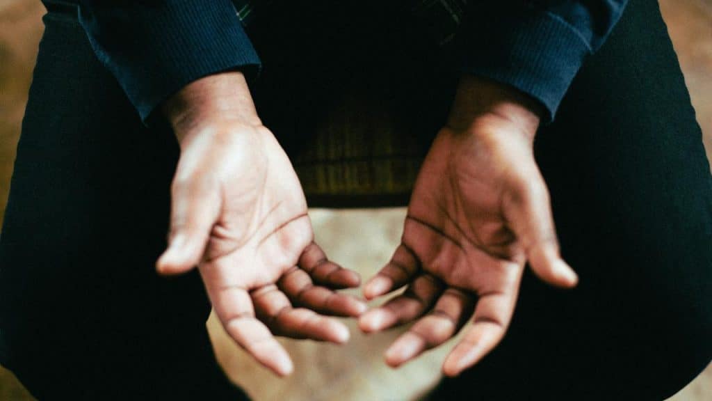 A person sitting with open hands resting on their knees.