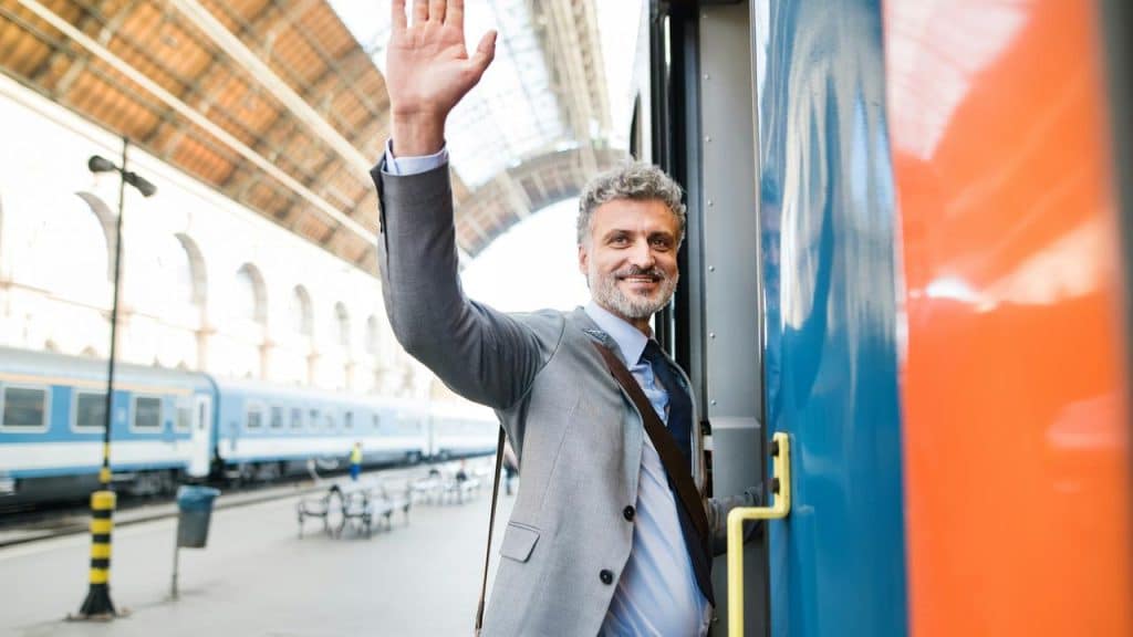 A man waving his hand while boarding a train.