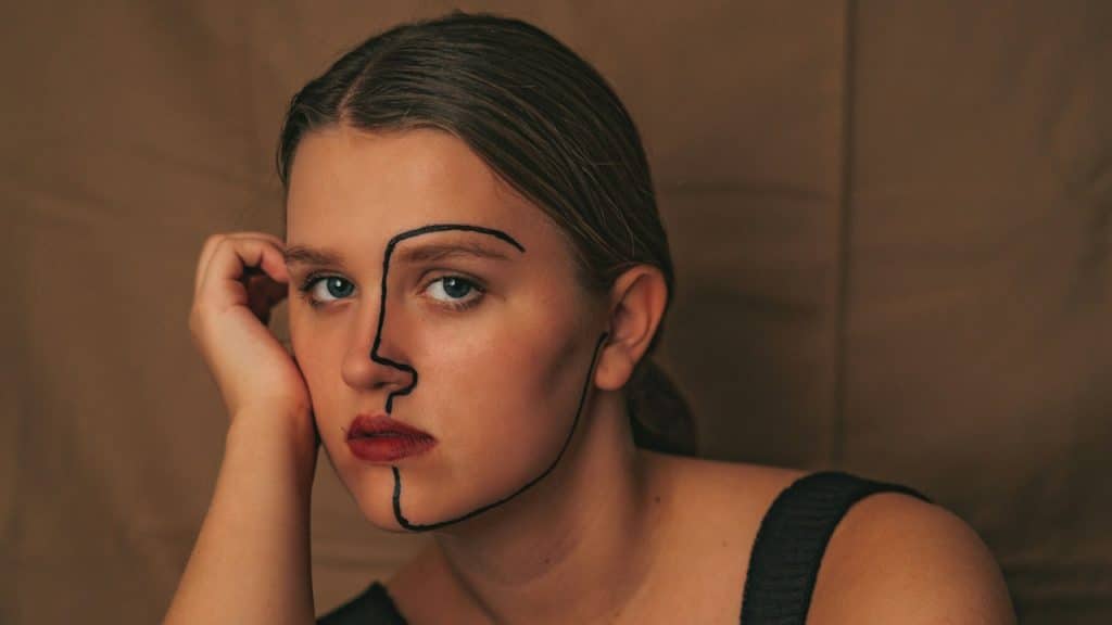 A woman looking at the camera with a strange mark on her face.