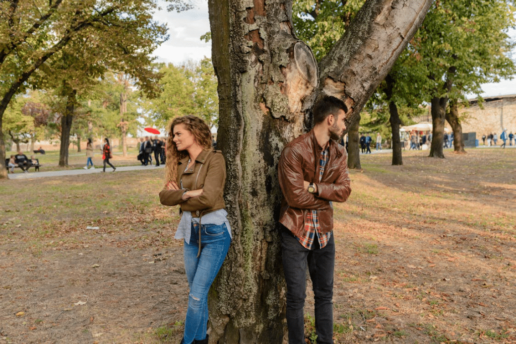 A man and a woman leaning on a tree