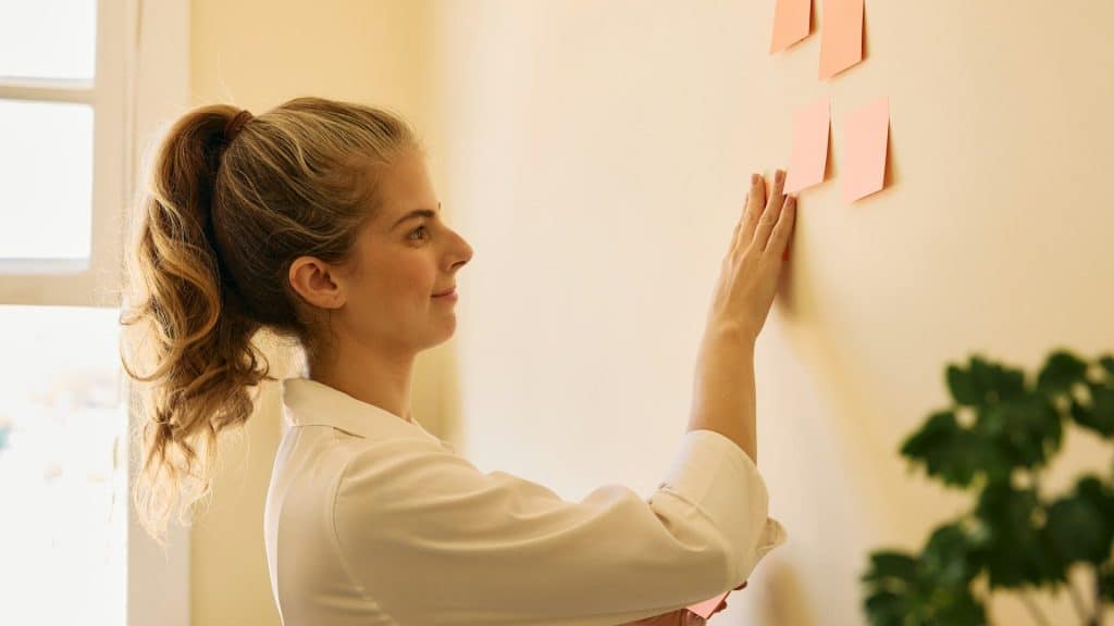 A woman sticking post-it-notes on the wall.