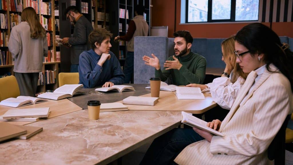 A group of people reading and discussing books at a library table.