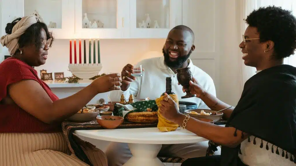 A group of adults laughing and sharing a meal around a dining table at home.