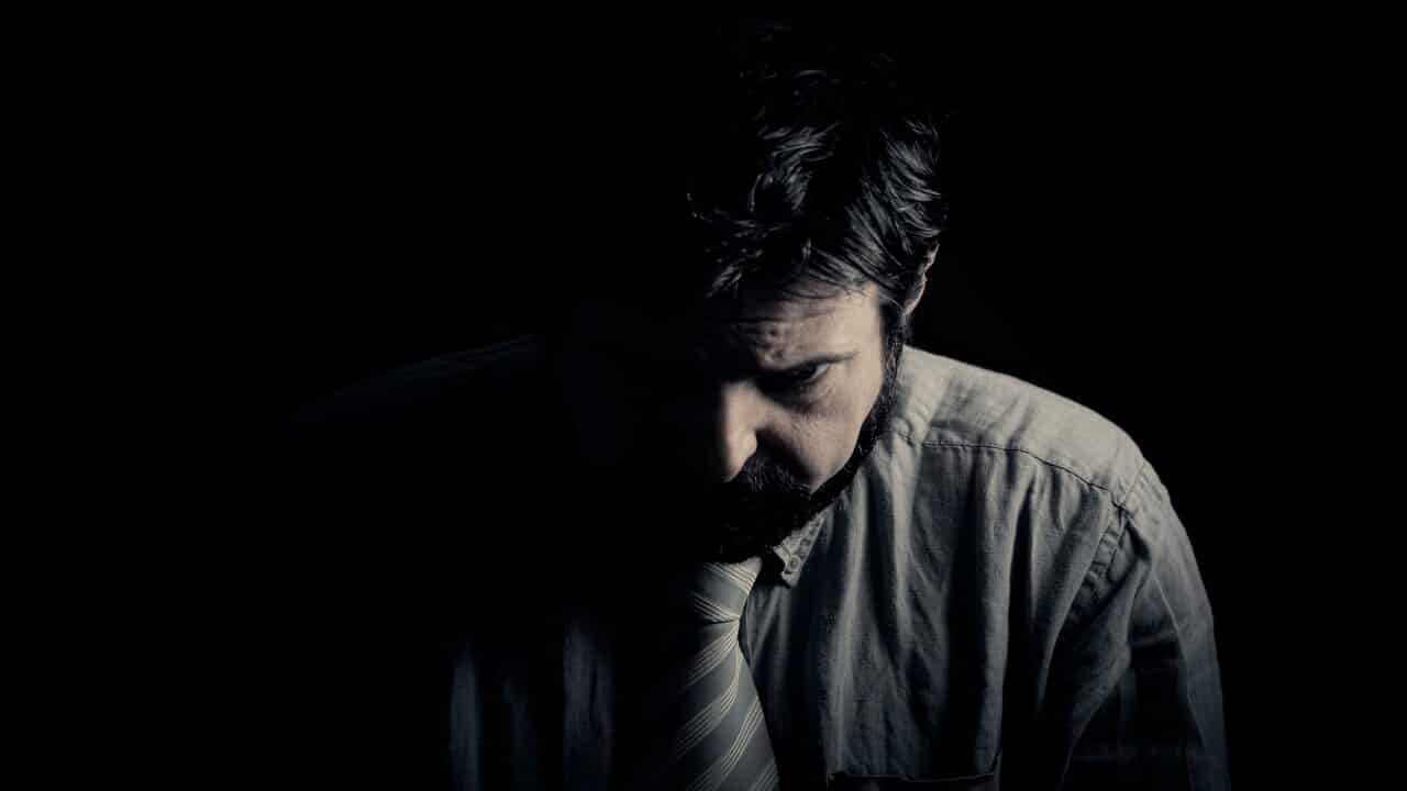 A man looking sad in the dark