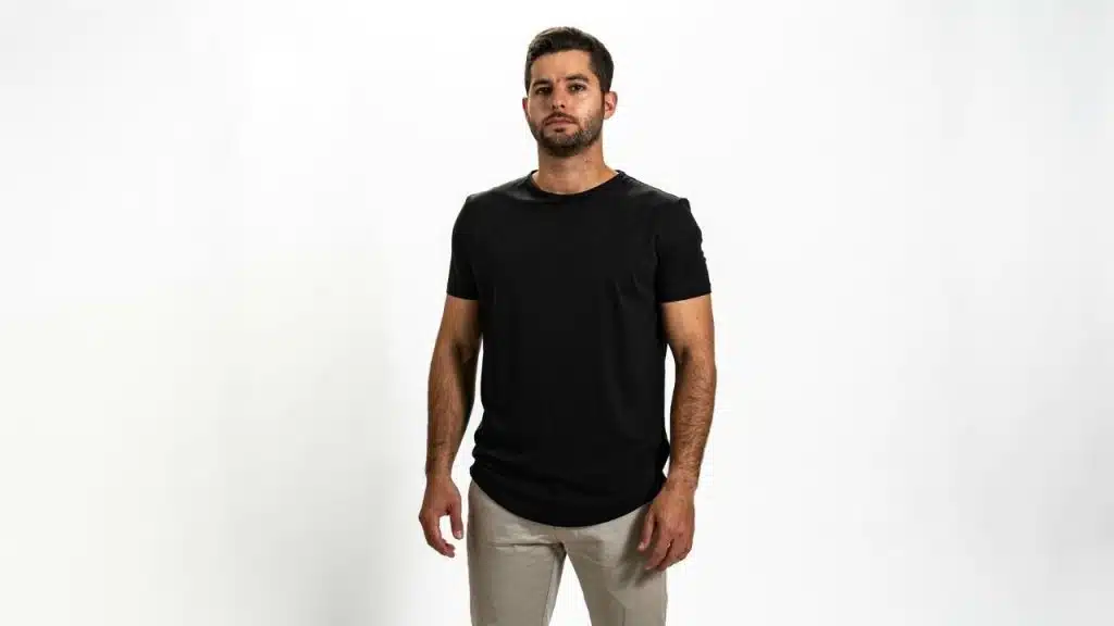 A man with a short beard stands facing forward wearing a black t-shirt.