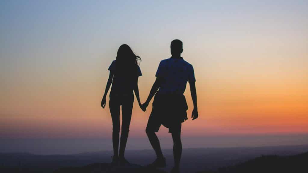 A man and woman holding hands in silhouette photography.
