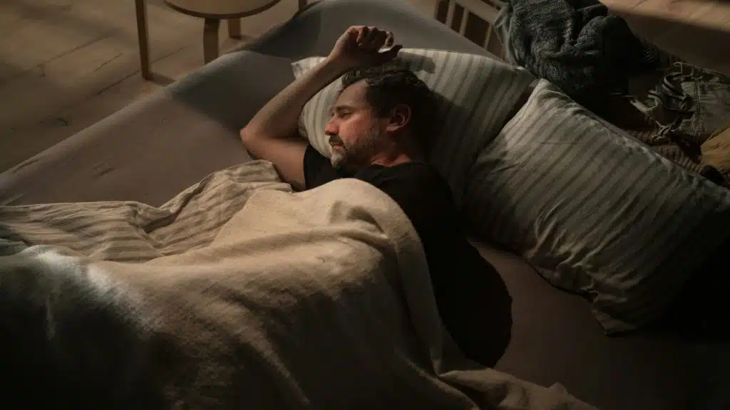 A sad man lying in bed