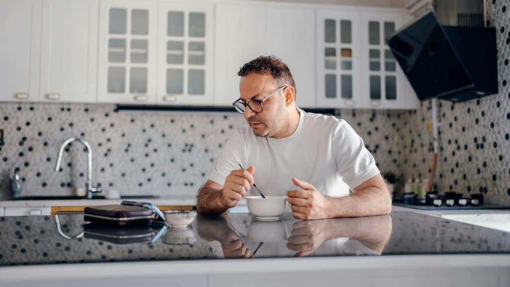 A man eats breakfast at his kitchen counter.