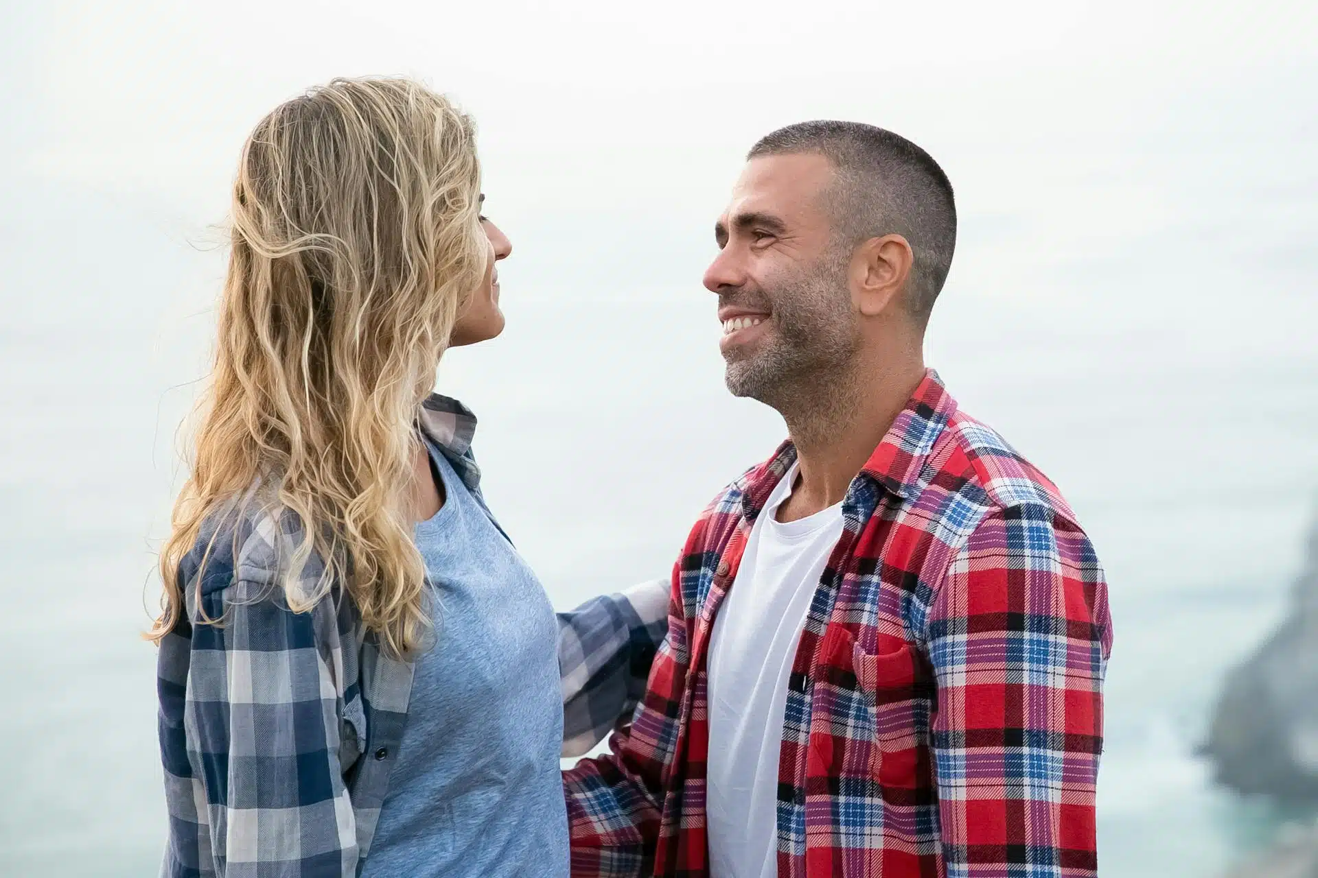 A couple standing face to face and smiling.