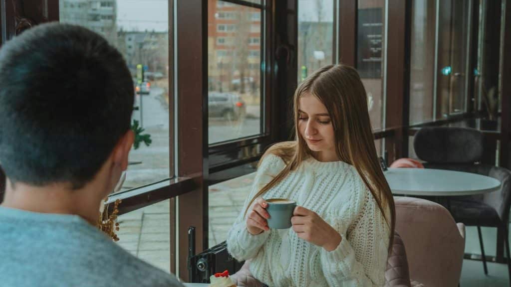 A woman holding a cup of coffee while sitting in a café.