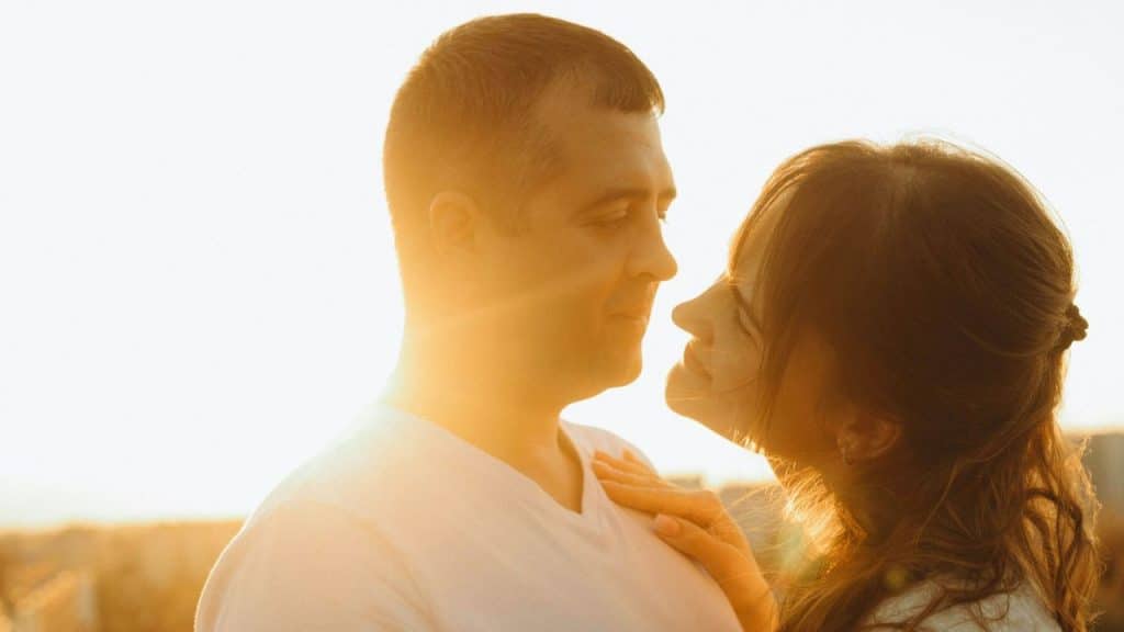 A man and a woman face each other outdoors, illuminated by a warm, bright sunset.