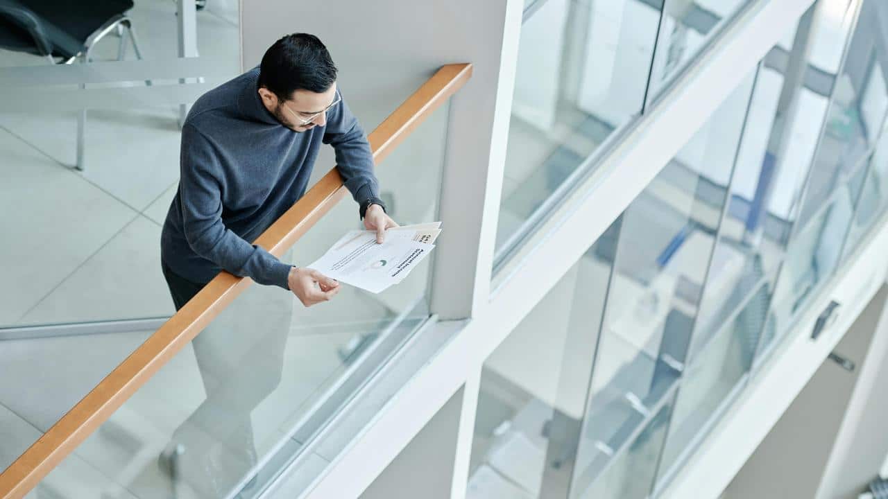 A man reading papers on a balcony.