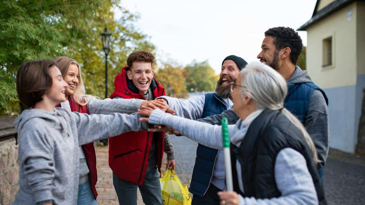 A group of people stacking hands outdoors.