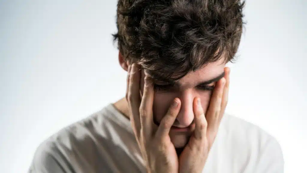A person holding their face with both hands in a distressed pose.