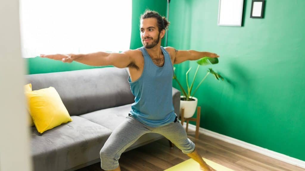 A man doing exercise in the living room of the room.