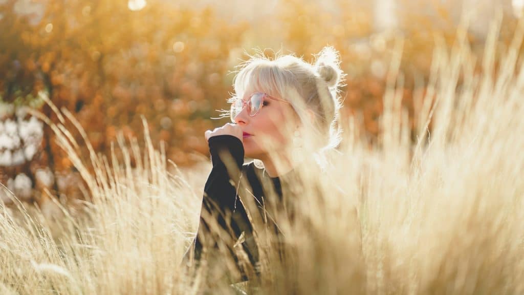 A woman sitting in a field with tall grass in daytime.